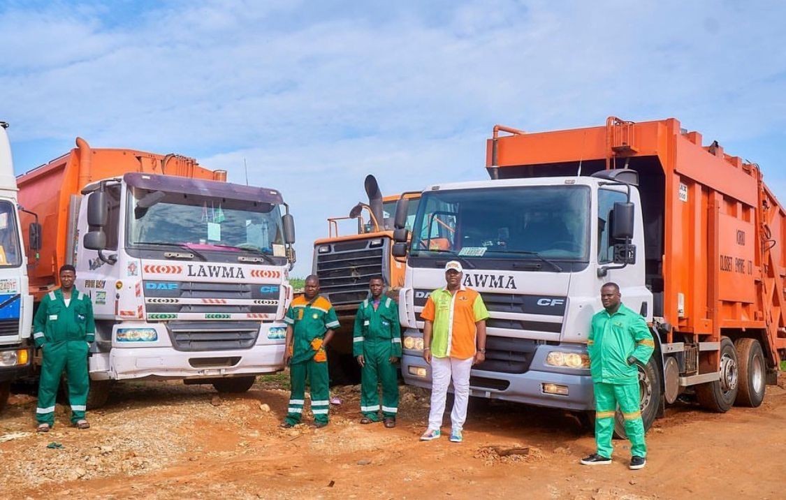 Futol Environmental Services team standing in front of LAWMA waste trucks, ready for environmental cleanup in Lagos.